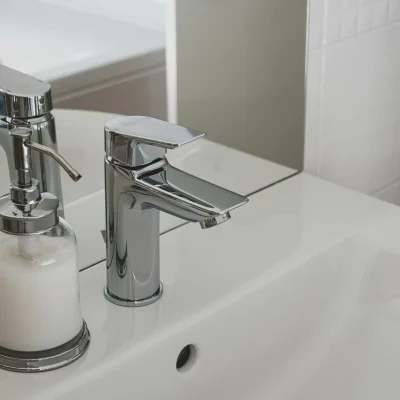Modern chrome faucet installed on white ceramic basin