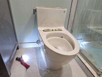 a toilet with a screwdriver and a screwdriver on the floor