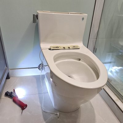 a toilet with a screwdriver and a screwdriver on the floor
